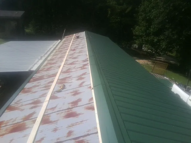 Old rusted panels beside newly installed green metal roofing — Wind Damage Roof Repair by Roofing Brothers in Manahawkin
