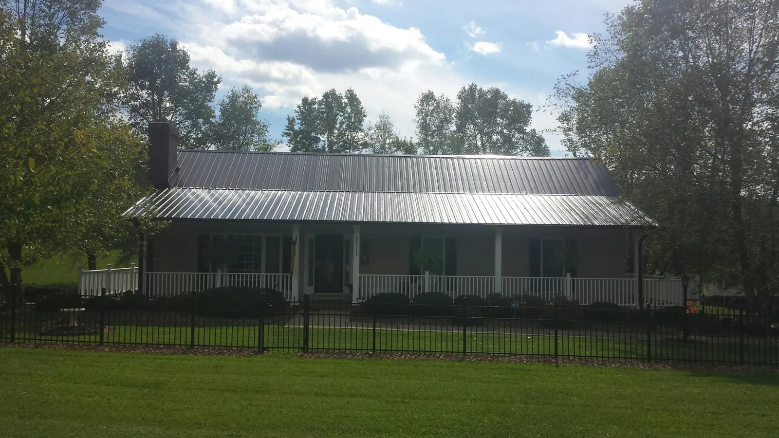 Gray metal roof on a brick ranch with a full width front porch — Gutter Guard Installation work by our crew in Manahawkin